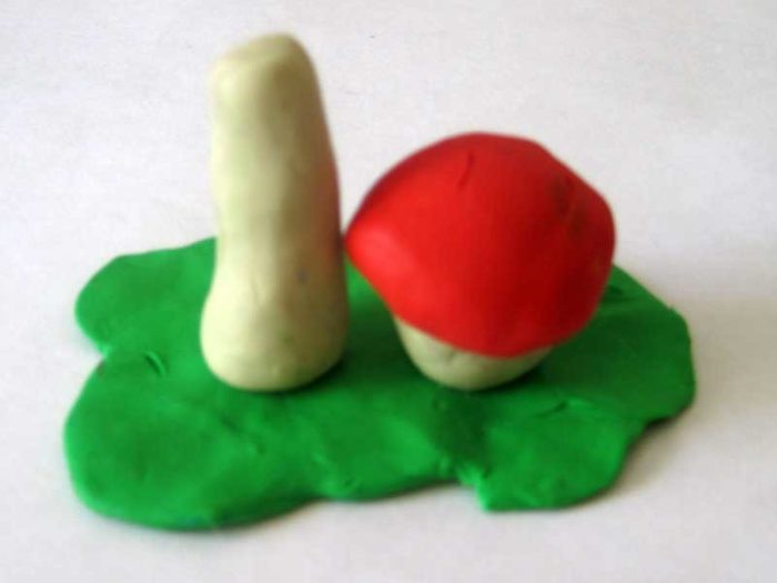 Ножка пластилинового гриба на основании, рядом пластилиновый гриб поменьше, со шляпкой